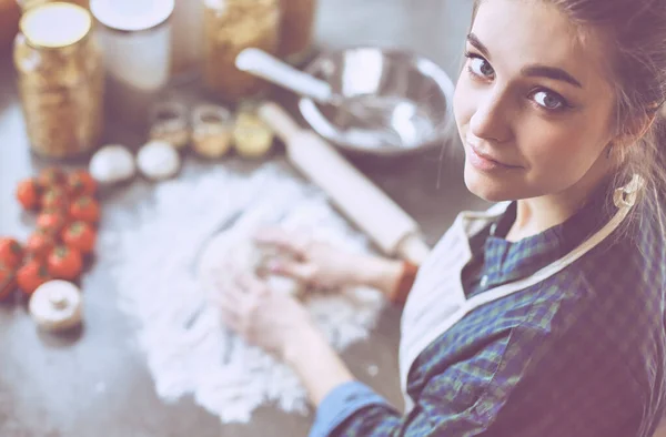 Красивая женщина готовит торт на кухне стоя возле стола — стоковое фото