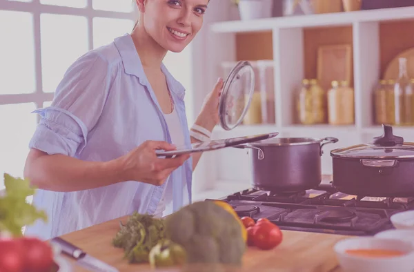 Jovem usando um computador tablet para cozinhar em sua cozinha. — Fotografia de Stock