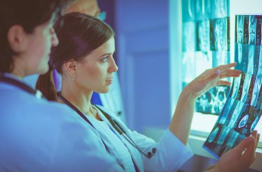 Bir grup doktor bir klinikte röntgenleri inceliyor, teşhis koymayı düşünüyorlar.
