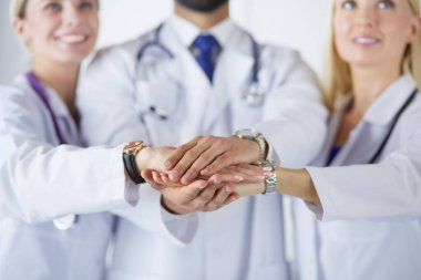 Doktorlar ve hemşireler tıbbi bir ekipte el ele tutuşuyorlar.