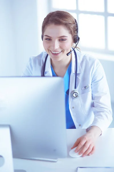 Dokter draagt een headset zittend achter een bureau met laptop — Stockfoto