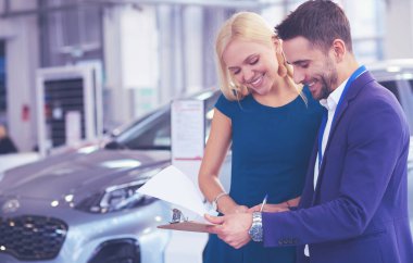 Araba satıcısı araba galerisindeki mutlu müşteriye araba satar ve anahtarları teslim eder.