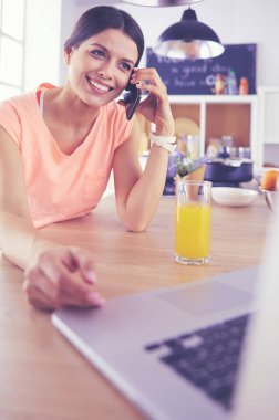Mutfakta dizüstü bilgisayara benzeyen tariflerle gülümseyen genç bir kadın. Gıda blogcusu kavramı