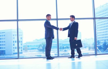 İki başarılı iş adamının el sıkışırken tam boy görüntüsü.