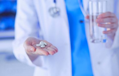 Doktorların ellerinde haplar ve bir bardak su tutarken yakın plan çekimleri..