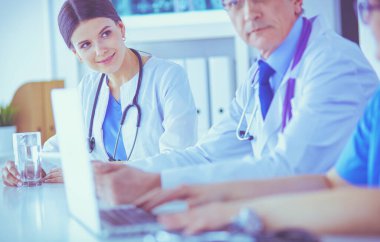 Parlak bir hastane odasında meslektaşlarıyla çalışan gülümseyen bir doktor.