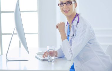 Hastanede masasında oturan genç bir kadın doktorun portresi.