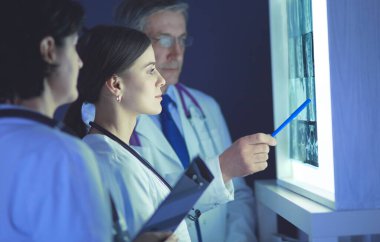 Bir grup doktor bir klinikte röntgenleri inceliyor, teşhis koymayı düşünüyorlar.