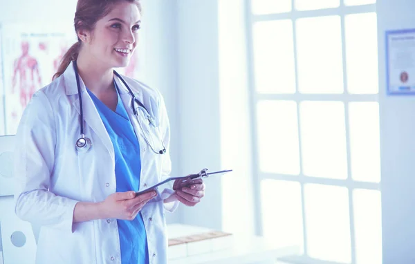 Médica sorridente com uma pasta em pé uniforme — Fotografia de Stock