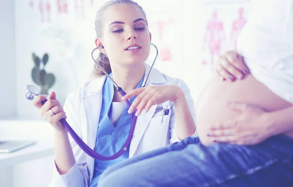 Doctora joven con estetoscopio hablando con una mujer embarazada en el hospital . — Foto de Stock