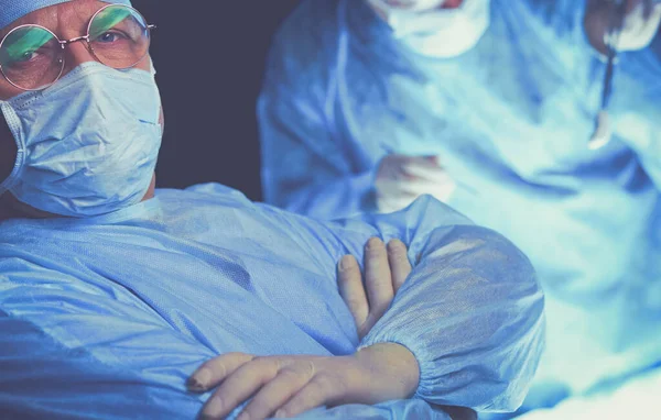 Group of surgeons at work in operating theater toned in blue. Medical team performing operation — Stock Photo, Image