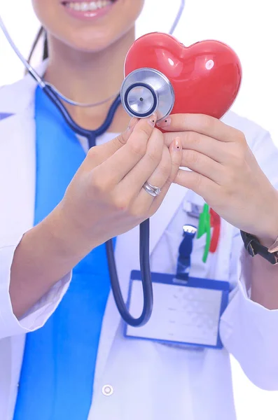 Médica feminina positiva em pé com estetoscópio e símbolo de coração vermelho isolado. Mulher médica — Fotografia de Stock