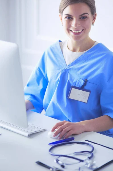 Young tired exhausted woman sitting at desk, working on computer with medical documents