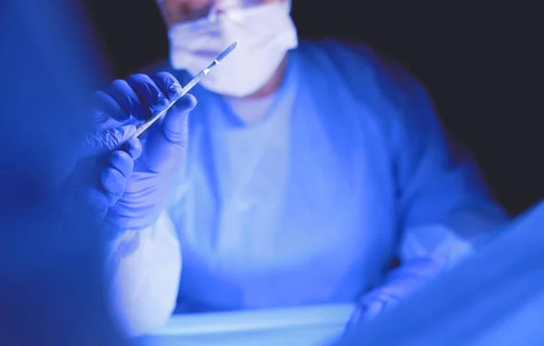 Lékař provádějící operaci v tmavém pozadí. — Stock fotografie