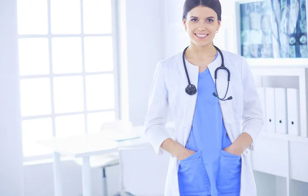 Vrouwelijke arts staat met stethoscoop en haar handen in zakken in het ziekenhuis — Stockfoto