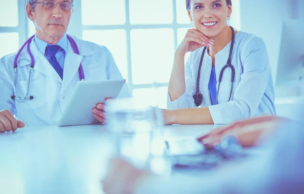Médico sorridente usando um laptop trabalhando com seus colegas em um quarto de hospital brilhante — Fotografia de Stock