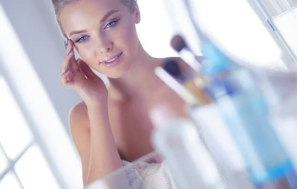 Молода жінка в халаті дивиться у дзеркало у ванній — стокове фото
