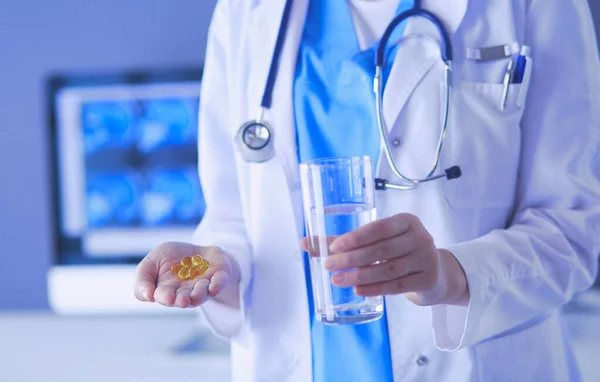 Tiro de médicos mãos segurando pílulas e vidro de água na clínica. — Fotografia de Stock