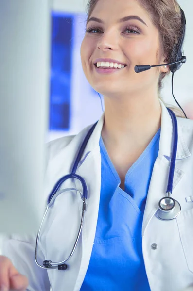 Young practitioner doctor working at the clinic reception desk, she is answering phone calls and scheduling appointments — Stock Photo, Image