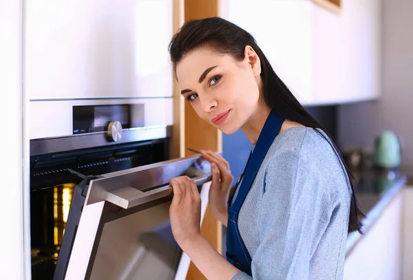 Mulher bonita verificando como seu bolo está indo no forno — Fotografia de Stock