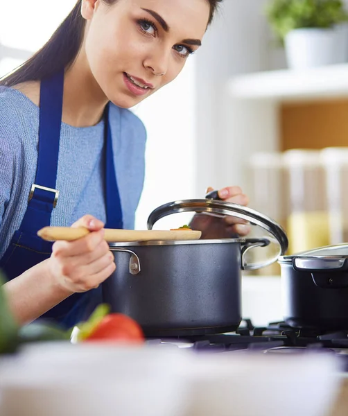 Mutfakta ahşap kaşıkla yemek pişiren kadın