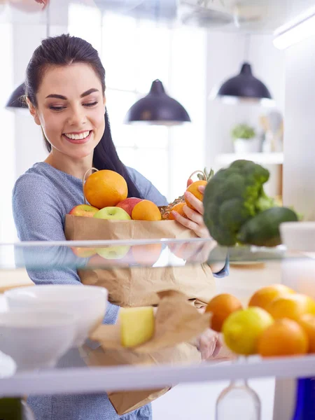 Mosolygó nő vesz egy friss gyümölcsöt ki a hűtőből, egészséges étel koncepció — Stock Fotó