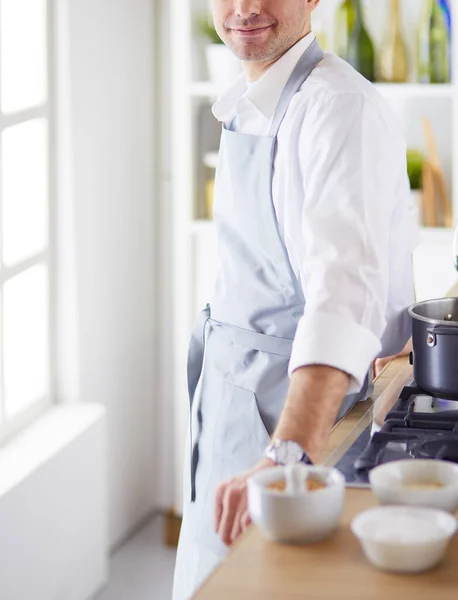 Handsome man is cooking on kitchen and smiling