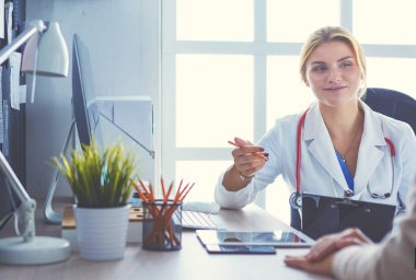 Kadın doktor hastaya danışmanlık yaparken başvuru formu tutuyor