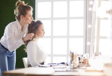 Makyöz, genç bir kadının profesyonel makyajını yapıyor.