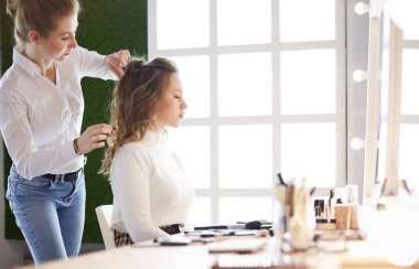 Makyöz, genç bir kadının profesyonel makyajını yapıyor.