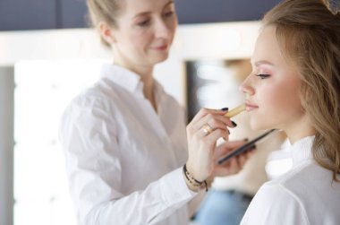 Güzel, genç bir model kadın makyaj yaptırıyor.