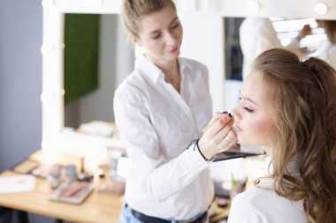 Güzel, genç bir model kadın makyaj yaptırıyor.