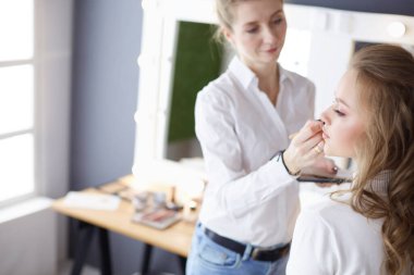 Güzel, genç bir model kadın makyaj yaptırıyor.