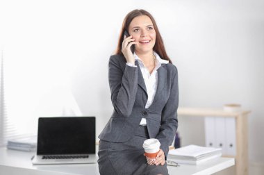 Modern ofiste telefonla konuşan başarılı, güzel bir kadın. Güzel, başarılı bir kadın.