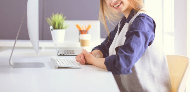 Ofis masasında çalışan ve dizüstü bilgisayarla yazan kendine güvenen genç bir iş kadını.