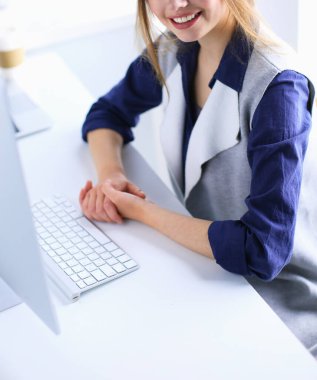 Ofis masasında çalışan ve dizüstü bilgisayarla yazan kendine güvenen genç bir iş kadını.