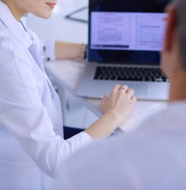 Ciddi bir tıbbi ekip parlak bir ofiste dizüstü bilgisayar kullanıyor.