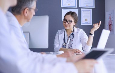 Ciddi bir tıbbi ekip parlak bir ofiste dizüstü bilgisayar kullanıyor.