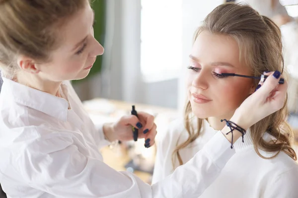 Mladá krásná nevěsta použití svatební make-up profesionální make-up umělce — Stock fotografie