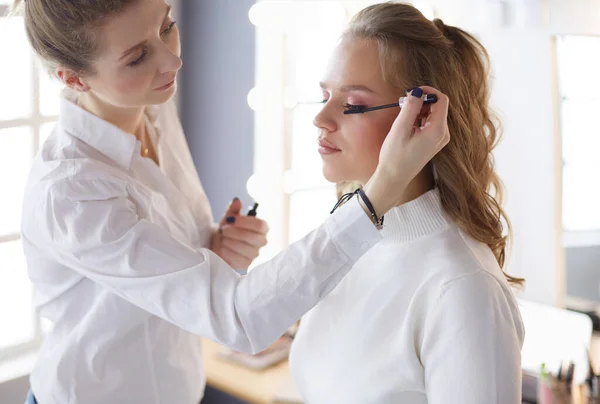 Jovem noiva bonita aplicando maquiagem de casamento por artista de maquiagem profissional — Fotografia de Stock
