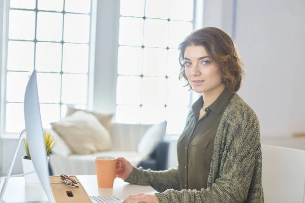Mladá hezká žena s kávou a pomocí notebooku na pohovce doma — Stock fotografie