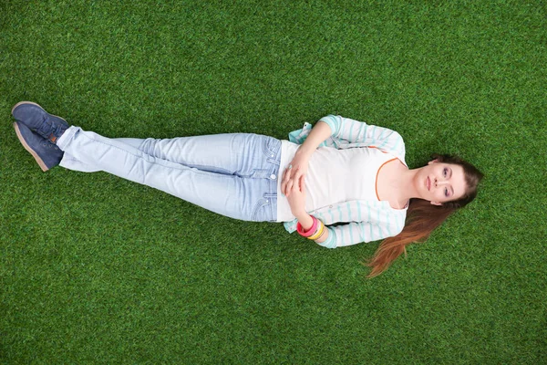 Vacker ung kvinna ligger på det gröna gräset — Stockfoto