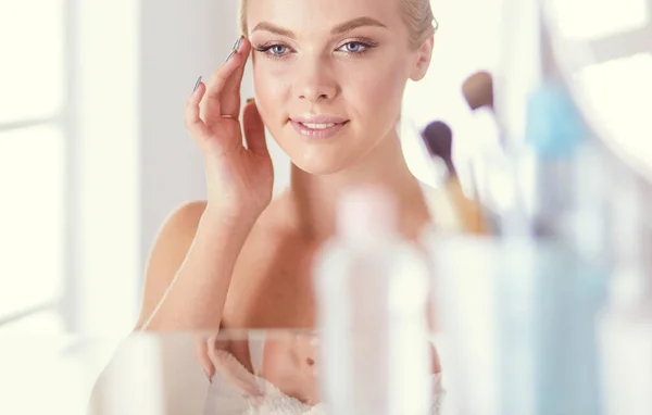 Young woman in bathrobe looking in bathroom mirror — Stock Photo, Image