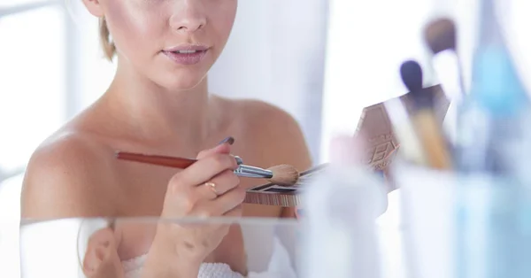 Een foto van een jonge vrouw die gezichtspoeder in de badkamer aanbrengt — Stockfoto