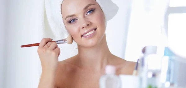 Uma foto de uma jovem mulher aplicando pó facial no banheiro — Fotografia de Stock