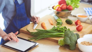 Mutfakta sebze doğrayan genç bir kadın.