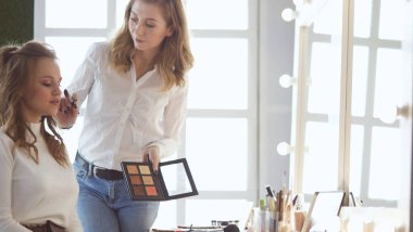 Makyöz, genç bir kadının profesyonel makyajını yapıyor.