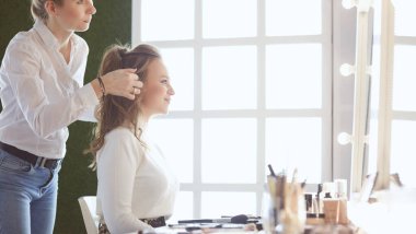 Makyöz, genç bir kadının profesyonel makyajını yapıyor.