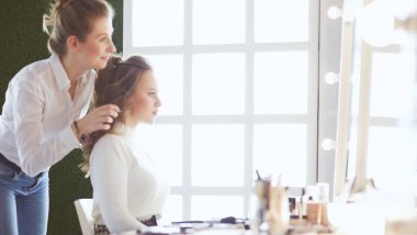 Makyöz, genç bir kadının profesyonel makyajını yapıyor.