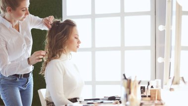 Makyöz, genç bir kadının profesyonel makyajını yapıyor.